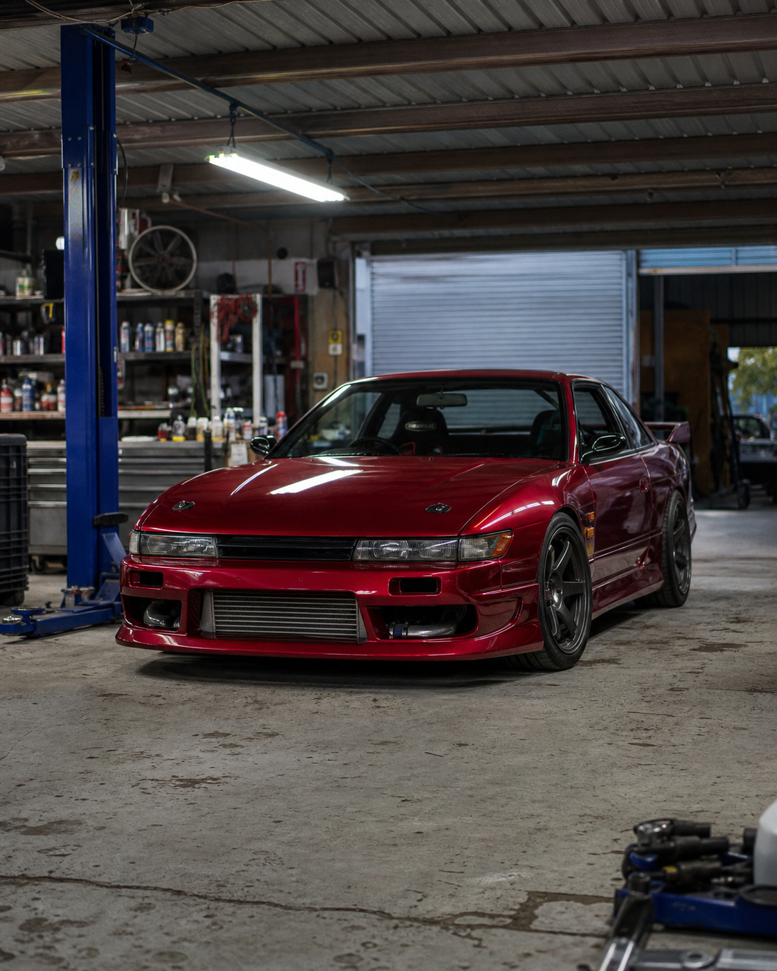 Modified red performance coupe in a tuning garage